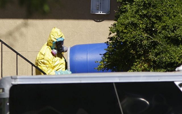 A hazardous material cleaner removes a blue barrel from the apartment in Dallas, Friday, Oct. 3, 2014, where Thomas Eric Duncan, the Ebola patient who traveled from Liberia to Dallas, stayed (photo credit: AP Photo/LM Otero) A hazardous material cleaner removes a blue barrel from the apartment in Dallas, Friday, Oct. 3, 2014, where Thomas Eric Duncan, the Ebola patient who traveled from Liberia to Dallas, stayed (photo credit: AP Photo/LM Otero)