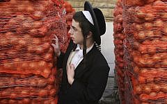 A haredi youth stands next to piles of potatoes in Jerusalem (Photo credit: Matanya Tausig/Flash90)