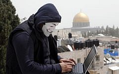 A Palestinian in a Guy Fawkes mask on a computer in Jerusalem, April 8, 2013. (photo credit: Sliman Khader/Flash90)
