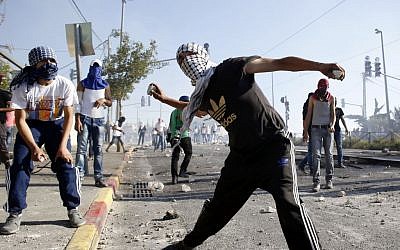Masked Palestinian protesters throw stones towards Israeli police during clashes in the Shuafat neighborhood in East Jerusalem. July 3, 2014. (photo credit: Sliman Khader/FLASH90) Masked Palestinian protesters throw stones towards Israeli police during clashes in the Shuafat neighborhood in East Jerusalem. July 3, 2014. (photo credit: Sliman Khader/FLASH90)