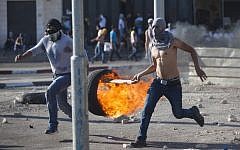 Illustrative photo of an East Jerusalem resident hurling a burning tire at Israeli security forces, on July 04, 2014 (photo credit: Yonatan Sindel/Flash90)