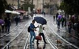 Israelis hold umbrellas to protect themselves from the rain as they walk on Jaffa Street, downtown Jerusalem, October 31, 2014. (Miriam Alster/Flash90)