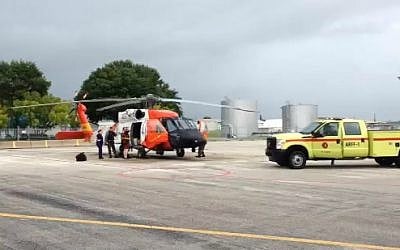 An MH-60 aircrew with Coast Guard Air Station Clearwater assists a man, longtime endurance runner and peace activist Reza Baluchi, they medically evacuated east of St. Augustine, Fla., Saturday, Oct. 4, 2014. (AP Photo/U.S. Coast Guard)