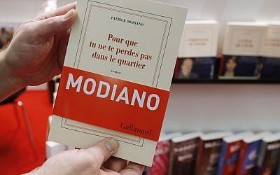 A man holds a book of French author Patrick Modiano at the Book Fair in Frankfurt, Germany, Thursday, Oct. 9, 2014. Modiano won this year's nobel prize for literature. (photo credit: AP Photo/Michael Probst)