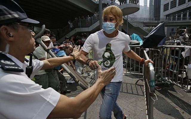 A police officer tries to stop a man removing the metal barricades that protesters have set up to block off main roads near the heart of the city's financial district. Hong Kong Monday, October 13, 2014. (photo credit: AP Photo/Vincent Yu) A police officer tries to stop a man removing the metal barricades that protesters have set up to block off main roads near the heart of the city's financial district. Hong Kong Monday, October 13, 2014. (photo credit: AP Photo/Vincent Yu)