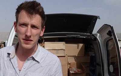 Peter Kassig next to a truck filled with supplies for Syrian refugees. A video produced by  the Islamic State in Syria released Friday, October 3, 2014, shows Kassig, of Indianapolis, kneeling on the ground as a masked militant says he will be killed next. (photo credit: AP/Courtesy Kassig Family)