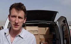 This undated photo provided by the Kassig family shows Peter Kassig standing in front of a truck filled with supplies for Syrian refugees. (photo credit: AP/Courtesy Kassig Family)