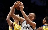 Brooklyn Nets' Brook Lopez (11) drives between a double team from Maccabi Tel Aviv's Jake Cohen, left, and Sylven Landesberg, right, during the first quarter of an NBA preseason basketball game Tuesday, Oct. 7, 2014, in New York. (photo credit: AP/Jason DeCrow)