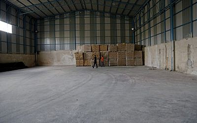Palestinian workers check bags of cement at a warehouse fitted with security cameras where UN monitors carry out periodic inspections to make sure the materials are not diverted by Hamas for military use, Shijaiyah neighborhood in Gaza City in the northern Gaza Strip, Wednesday, Oct. 22, 2014. (photo credit: AP/Adel Hana)