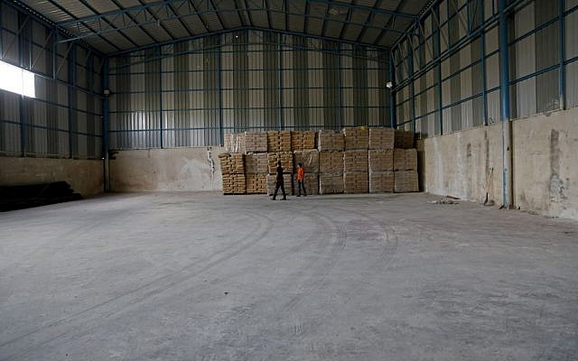 Palestinian workers check bags of cement at a warehouse fitted with security cameras where UN monitors carry out periodic inspections to make sure the materials are not diverted by Hamas for military use, Shijaiyah neighborhood in Gaza City in the northern Gaza Strip, Wednesday, Oct. 22, 2014. (photo credit: AP/Adel Hana)