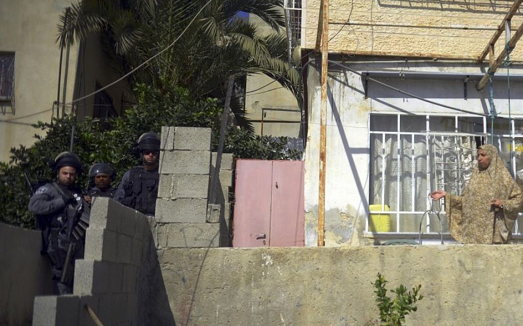 In this photo taken Tuesday, Sept. 30, 2014, a Palestinian woman stands in front of her Silwan apartment while Israeli police officers secure an alleyway leading to the entrance of a home that Jewish settlers had moved into. (AP Photo/Mahmoud Illean) In this photo taken Tuesday, Sept. 30, 2014, a Palestinian woman stands in front of her Silwan apartment while Israeli police officers secure an alleyway leading to the entrance of a home that Jewish settlers had moved into. (AP Photo/Mahmoud Illean)