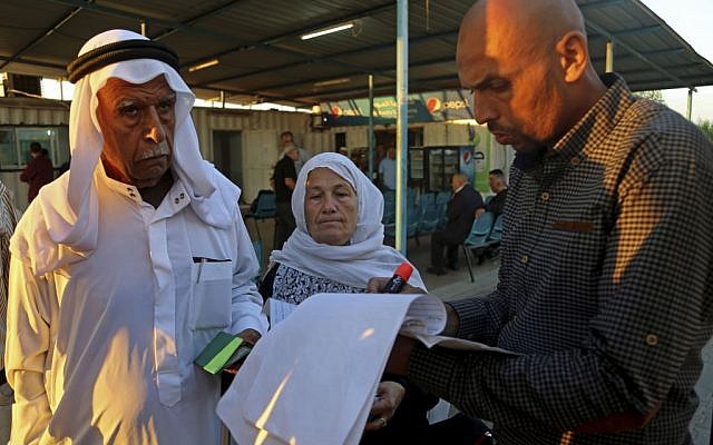 A Palestinian worker checks a list of names of registered Muslim pilgrims waiting to cross the Erez border crossing between Israel and Gaza headed to Jerusalem during the three-day holiday of Eid al-Adha, in the northern Gaza Strip, Sunday, October 5, 2014. (photo credit: AP/Adel Hana) A Palestinian worker checks a list of names of registered Muslim pilgrims waiting to cross the Erez border crossing between Israel and Gaza headed to Jerusalem during the three-day holiday of Eid al-Adha, in the northern Gaza Strip, Sunday, October 5, 2014. (photo credit: AP/Adel Hana)