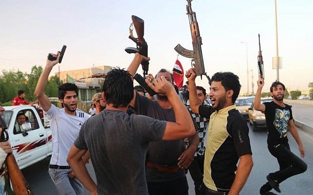In this Sunday, June 15, 2014 file photo, Shiite tribal fighters raise their weapons and chant slogans against the al-Qaida-inspired Islamic State group in Basra, Iraq's second-largest city, 340 miles (550 kilometers) southeast of Baghdad, Iraq. (Photo credit: AP/ Nabil Al-Jurani)