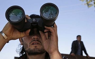 A Turkish Kurd, standing on the Turkey-Syria border, uses binoculars to watch fighting between militants of the Islamic State group and Kurdish forces in Kobani, Syria, on outskirts of Suruc, Turkey, on October 6, 2014. (photo credit: AP Photo/Lefteris Pitarakis)