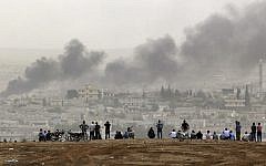 People on a hilltop watch smoke rising from a fire caused by a strike in Kobani, Syria, during fighting between Syrian Kurds and the militants of Islamic State group, on the outskirts of Suruc, at the Turkey-Syria border, on October 11, 2014. (AP Photo/Lefteris Pitarakis, File)