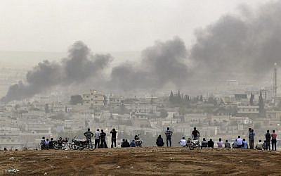 People on a hilltop watch smoke rising from a fire caused by a strike in Kobani, Syria, during fighting between Syrian Kurds and the militants of Islamic State group, on the outskirts of Suruc, at the Turkey-Syria border, on October 11, 2014. (AP Photo/Lefteris Pitarakis, File)