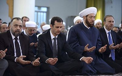 Syrian President Bashar Assad, center, prays during Eid al-Adha prayers at a mosque in Damascus, Syria, October 4, 2014. (photo credit: AP/SANA) Syrian President Bashar Assad, center, prays during Eid al-Adha prayers at a mosque in Damascus, Syria, October 4, 2014. (photo credit: AP/SANA)