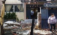 FILE: In this photo released by the Syrian official news agency SANA, Syrian citizens check the damaged school entrance in Akrama neighborhood in Homs province, Syria, Wednesday, October 1, 2014. (AP Photo/SANA)