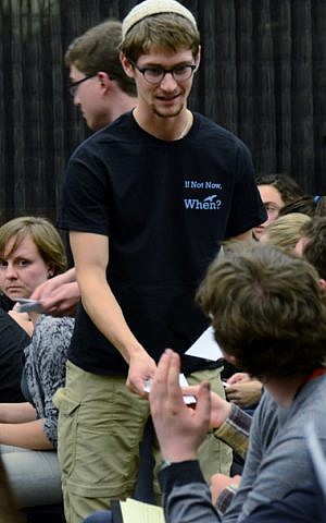 Henry Rosen, a student organizer for the Open Hillel conference at Harvard, handing out material at a plenary session, Oct. 12, 2014. (Gili Getz/JTA)