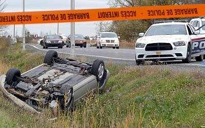 A car is overturned in the ditch in a cordoned off area in St-Jean-sur-Richelieu, Quebec on Monday Oct. 20, 2014. One of two soldiers hit by a car died of his injuries early Tuesday, according to Quebec provincial police. Provincial police say the man sped off in his car after hitting the two soldiers in the parking lot of a shopping mall, starting a chase that ended with the man losing control and his car rolling over several times. The driver died from police gunfire. (Photo credit: AP/The Canadian Press,Pascal Marchand)