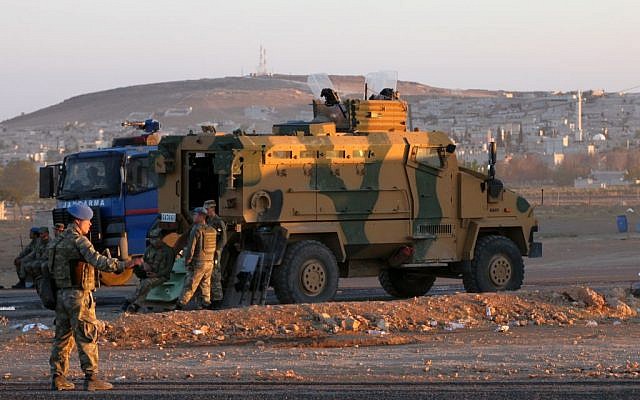 Turkish soldiers stand guard at a checkpoint as Syrian refugees from Kobani arrive at the Turkey-Syria border crossing of Mursitpinar near Suruc, Turkey, late Wednesday, October 1, 2014. (photo credit: AP Photo/Burhan Ozbilici)