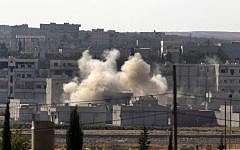 Smoke rises after a shell landed in Kobani in Syria as fighting intensified between Syrian Kurds and the militants of Islamic State group, as seen from Mursitpinar near Suruc, at the Turkey-Syria border, Sunday, October 5, 2014. (photo credit: AP Photo/Lefteris Pitarakis)