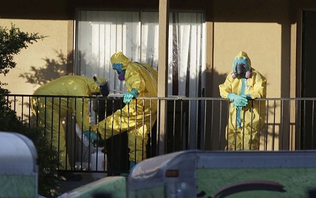 In this Oct. 5, 2014 file photo, hazardous material cleaners disinfectant their personal protective equipment after working in the apartment where Thomas Eric Duncan, the Ebola patient who traveled from Liberia to Dallas, stayed in Dallas. (Photo credit: AP/LM Otero, File) In this Oct. 5, 2014 file photo, hazardous material cleaners disinfectant their personal protective equipment after working in the apartment where Thomas Eric Duncan, the Ebola patient who traveled from Liberia to Dallas, stayed in Dallas. (Photo credit: AP/LM Otero, File)