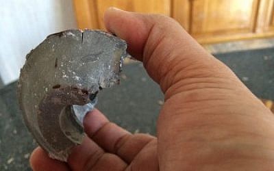 Barzak holding up a piece of a missile that hit his home this summer during Operation Protective Edge. (photo credit: Ibrahim Barzak/JTA)