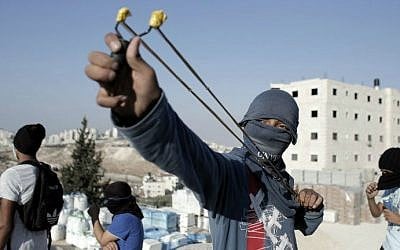 A Palestinian protester holds a slingshot during clashes with Israeli police (unseen) in a suburb of East Jerusalem on October 23, 2014. (photo credit: AFP PHOTO / Ahmad Gharabli) 