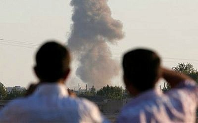 Turkish Kurds standing on the outskirts of Suruc, on the Turkey-Syria border, watch smoke rise following an airstrike in Kobani, Syria, where the fighting between militants of the Islamic State group and Kurdish forces intensified, Tuesday, Oct. 7, 2014 (photo credit: AP/Lefteris Pitarakis)