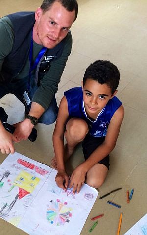 Adam Kawalek with a child, drawing a picture of his life during this summer's conflict and what he hopes his life will be like, at a community based organization in Gaza staffed by War Child. (Courtesy of Adam Kawalek)