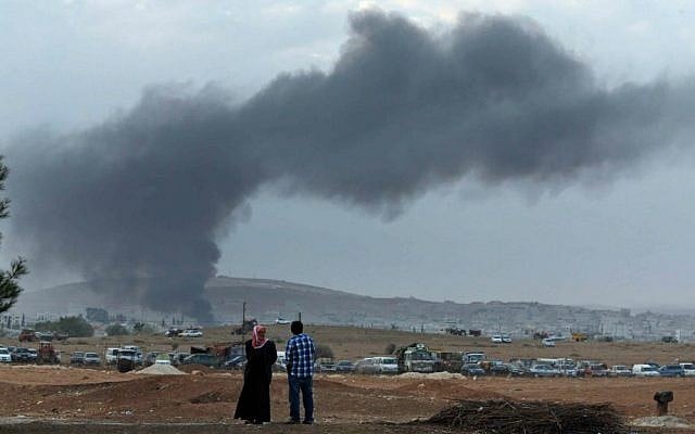 Residents of Mursitpinar on the outskirts of Suruc, at the Turkey-Syria border, watch as thick smoke rises following an airstrike by the US-led coalition in Kobani, Syria while fighting continued between Syrian Kurds and the Islamic State group, Tuesday, Oct. 14, 2014. (AP Photo/Lefteris Pitarakis)