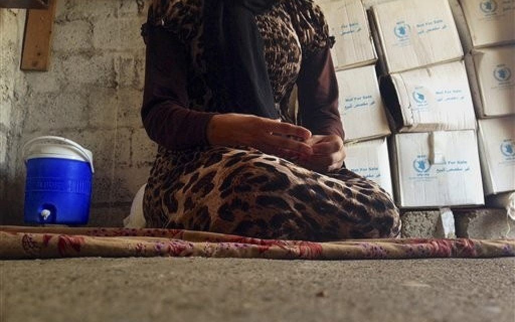 In this photo taken Wednesday, Oct. 8, 2014, a 15-year-old Yazidi girl captured by the Islamic State group and forcibly married to a militant in Syria sits on the floor of a one-room house she now shares with her family after escaping in early August, while speaking in an interview with The Associated Press in Maqluba, a hamlet near the Kurdish city of Dahuk, 260 miles (430 kilometers) northwest of Baghdad, Iraq. Her face is not shown. (photo credit: AP Photo/Dalton Bennett) In this photo taken Wednesday, Oct. 8, 2014, a 15-year-old Yazidi girl captured by the Islamic State group and forcibly married to a militant in Syria sits on the floor of a one-room house she now shares with her family after escaping in early August, while speaking in an interview with The Associated Press in Maqluba, a hamlet near the Kurdish city of Dahuk, 260 miles (430 kilometers) northwest of Baghdad, Iraq. Her face is not shown. (photo credit: AP Photo/Dalton Bennett)