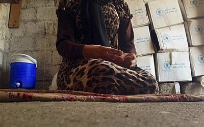 In this photo taken Wednesday, Oct. 8, 2014, a 15-year-old Yazidi girl captured by the Islamic State group and forcibly married to a militant in Syria sits on the floor of a one-room house she now shares with her family after escaping in early August, while speaking in an interview with The Associated Press in Maqluba, a hamlet near the Kurdish city of Dahuk, 260 miles (430 kilometers) northwest of Baghdad, Iraq. Her face is not shown. (photo credit: AP Photo/Dalton Bennett) In this photo taken Wednesday, Oct. 8, 2014, a 15-year-old Yazidi girl captured by the Islamic State group and forcibly married to a militant in Syria sits on the floor of a one-room house she now shares with her family after escaping in early August, while speaking in an interview with The Associated Press in Maqluba, a hamlet near the Kurdish city of Dahuk, 260 miles (430 kilometers) northwest of Baghdad, Iraq. Her face is not shown. (photo credit: AP Photo/Dalton Bennett)