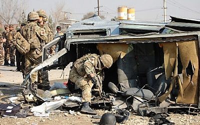 A NATO-led International Security Assistance Force (ISAF) soldier inspects a British embassy vehicle which was targeted in a suicide attack along the Kabul-Jalalabad road in Kabul on November 27, 2014. (photo credit: AFP/Daud Yardost)