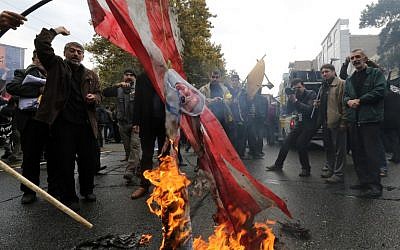 Iranians burn US flags outside the former US embassy in Tehran on November 4, 2014, during a demonstration to mark the anniversary of its storming by student protesters that triggered a hostage crisis. (photo credit: AFP/ATTA KENARE)