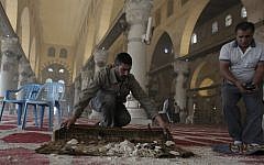 Palestinians clean up debris inside the Al-Aqsa Mosque, on November 5, 2014 following clashes between stone-throwing Palestinians and Israeli security forces. (photo credit:  AFP PHOTO/AHMAD GHARABLI)