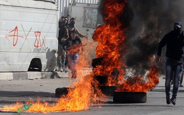 Palestinian protestors stand near burning tires during clashes with Israeli security forces in the West Bank city of Hebron on November 14, 2014 (Photo credit: Hazem Bader/AFP) Palestinian protestors stand near burning tires during clashes with Israeli security forces in the West Bank city of Hebron on November 14, 2014 (Photo credit: Hazem Bader/AFP)