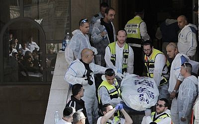 Israeli emergency services members carry a body at the scene of an attack at a synagogue in Jerusalem on November 18, 2014. (photo credit: AFP /AHMAD GHARABLI)