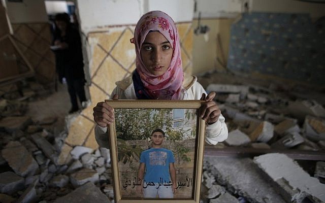 A relative of Abdel Rahman Shaludi, a Palestinian who killed two Israelis with his car last month, displays his portrait inside his family home after it was razed on November 19, 2014. (photo credit: AFP PHOTO/AHMAD GHARABLI)