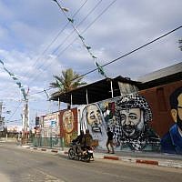 A Palestinian boy rides his bike past graffiti depicting (from L to R) late founder of the Popular Front for the Liberation of Palestine (PFLP) George Habash, late Hamas spiritual leader Sheikh Ahmed Yassin and late Palestinian leader Yasser Arafat, on November 21, 2014 in Gaza City. (photo credit: AFP/MOHAMMED ABED)