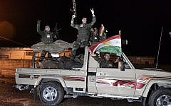 Kurdish peshmerga fighters gesture and wave a Kurdish flag from a military vehicle armed with a heavy infantry weapon as they ride towards the Syrian town of Kobani, also known as Ain al-Arab, from the border town of Suruc, in the Turkish southeastern Sanliurfa province, on October 31, 2014. (photo credit: AFP/STRINGER)