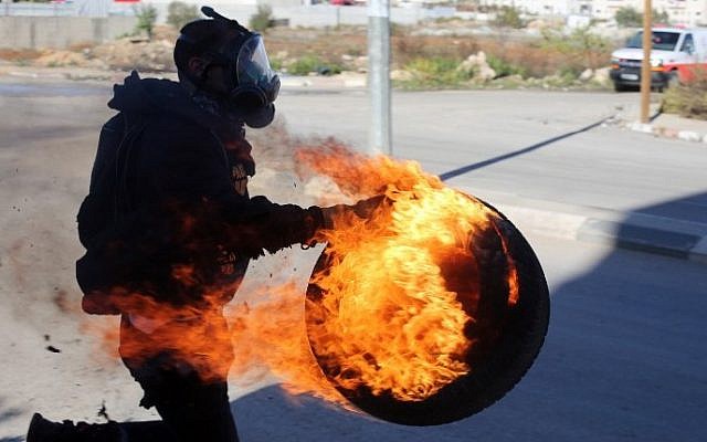 A Palestinian carries a lit tire during clashes between students from Birzeit University and Israeli soldiers (unseen) at the entrance to the Israeli Ofer military prison, near the West Bank village of Beitunia on November 6, 2014. (photo credit: AFP/Abbas Momani) A Palestinian carries a lit tire during clashes between students from Birzeit University and Israeli soldiers (unseen) at the entrance to the Israeli Ofer military prison, near the West Bank village of Beitunia on November 6, 2014. (photo credit: AFP/Abbas Momani)