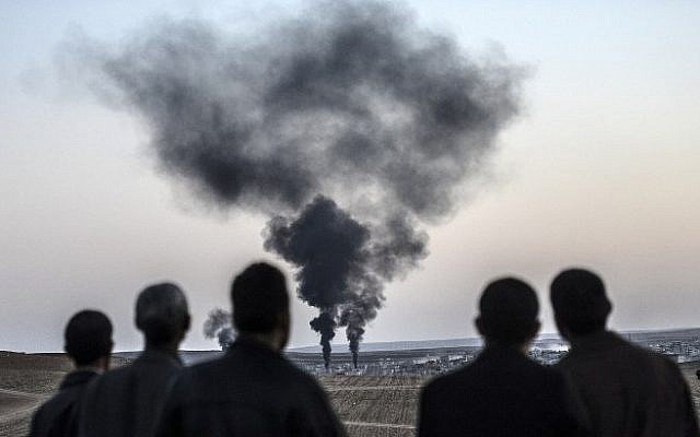 People watch as smokes rises from the town of Kobani on October 26, 2014, at the Turkish border near the southeastern village of Mursitpinar, Sanliurfa province. (Photo credit: AFP / BULENT KILIC)