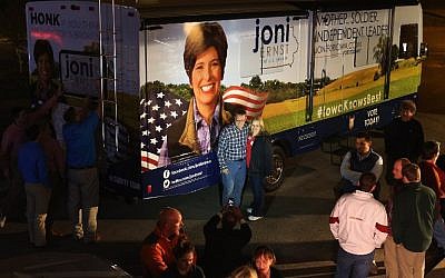 People pose with Republican US Senate candidate Joni Ernst's campaign RV outside the Alpha Gamma Rho fraternity house on the campus of Iowa State University on November 3, 2014 in Ames, Iowa. photo credit: Chip Somodevilla/Getty Images/AFP)