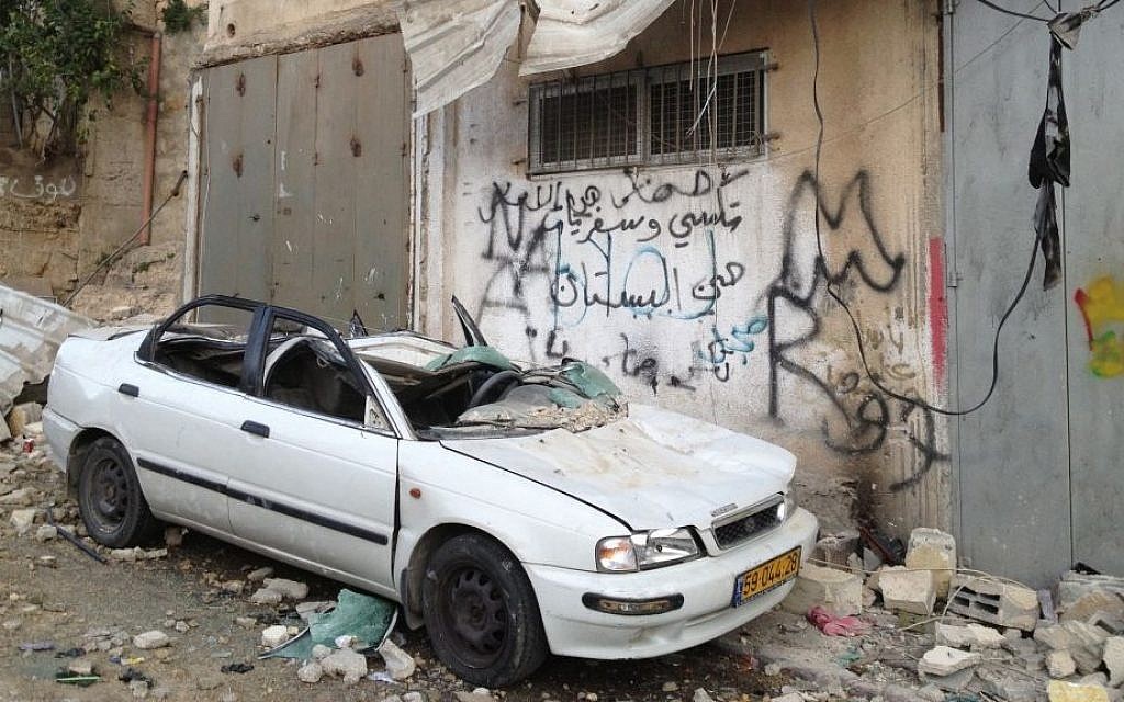 A car stands destroyed beneath the bombed out home of Palestinian terrorist Abdul Rahman Al-Shaloudi in Silwan, November 19, 2014 [photo credit: Elhanan Miller/Times of Israel]