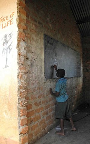 A child practices homework on a chalkboard at the Hadassah primary school. (Melanie Lidman/Times of Israel)
