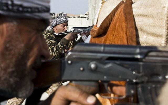 In this Wednesday, Nov. 19, 2014 photo, fighters from the Free Syrian Army, left, and the Kurdish People's Protection Units (YPG), center, join forces to fight Islamic State group militants in Kobani, Syria.  (Photo credit: AP/Jake Simkin)