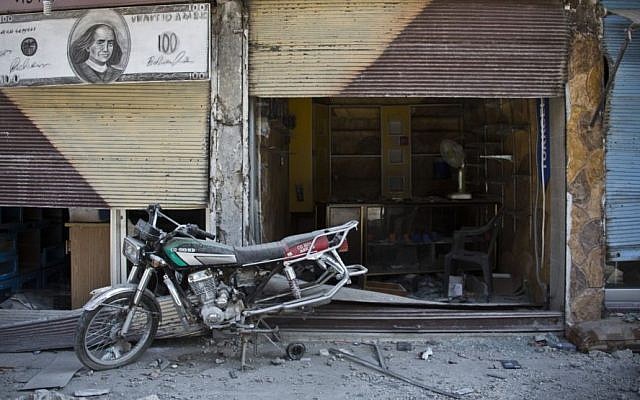 In this Wednesday, Nov. 19, 2014 photo, a motorcycle is left behind near shops destroyed by the fighting in Kobani, Syria. (Photo credit:AP/Jake Simkin)