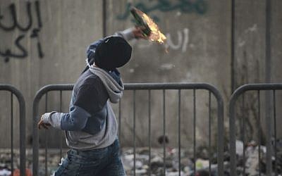 Illustrative photo of a Palestinian throwing a Molotov cocktail at Israeli forces at the entrance to the Shuafat refugee camp on November 05, 2014. (Hadas Parush/FLASH90)